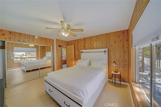 bedroom with a closet, ceiling fan, light wood-type flooring, and wood walls