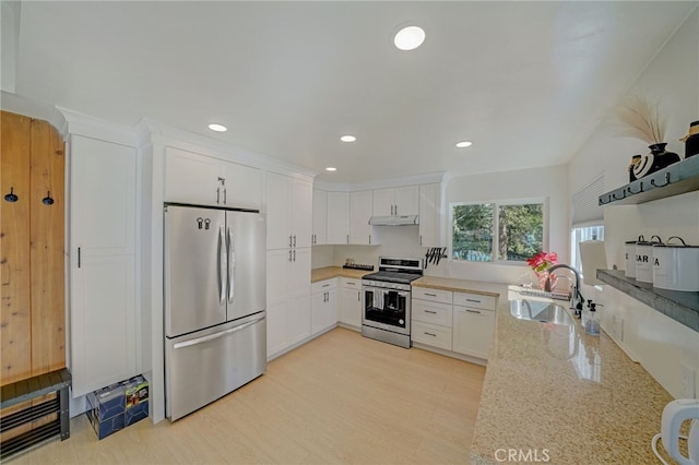 kitchen with sink, white cabinetry, stainless steel appliances, light stone countertops, and light hardwood / wood-style floors