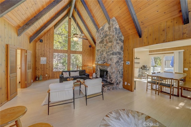 living room with a fireplace, wood walls, beamed ceiling, wooden ceiling, and light wood-type flooring