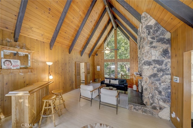 unfurnished living room with wood ceiling, wooden walls, high vaulted ceiling, bar area, and beamed ceiling