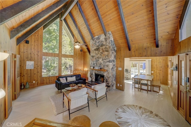 living room with wood ceiling, beam ceiling, wooden walls, and a stone fireplace