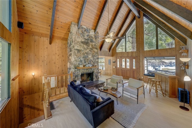 living room with a fireplace, wooden walls, high vaulted ceiling, and beam ceiling