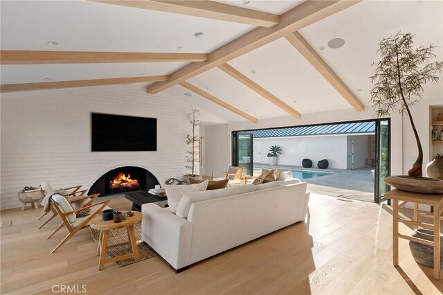 living room with vaulted ceiling with beams and light wood-type flooring