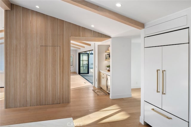 interior space with vaulted ceiling with beams, light hardwood / wood-style floors, and paneled built in refrigerator