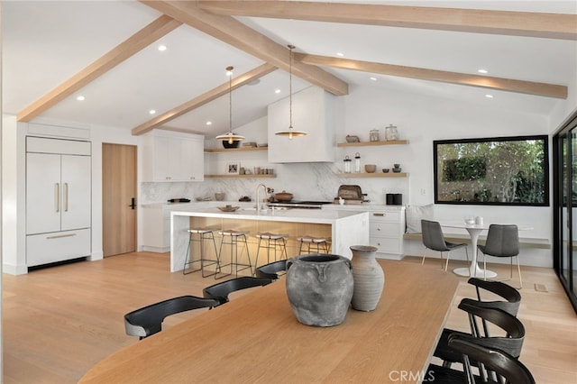 dining room featuring vaulted ceiling with beams, sink, and light wood-type flooring