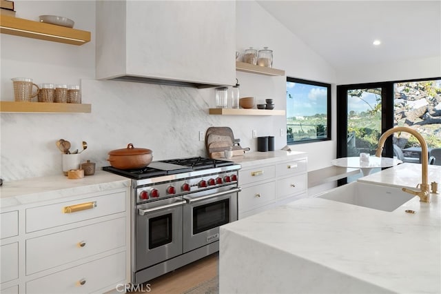 kitchen with premium range hood, sink, light stone counters, white cabinetry, and double oven range