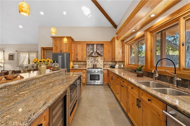 kitchen with wall chimney range hood, sink, premium appliances, light stone countertops, and decorative light fixtures