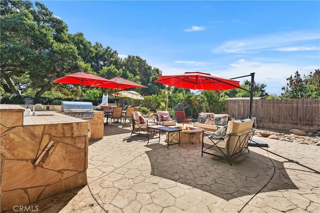 view of patio with area for grilling, sink, an outdoor fire pit, and exterior kitchen