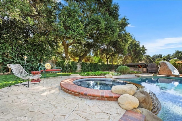 view of pool featuring an in ground hot tub, a patio, and a water slide