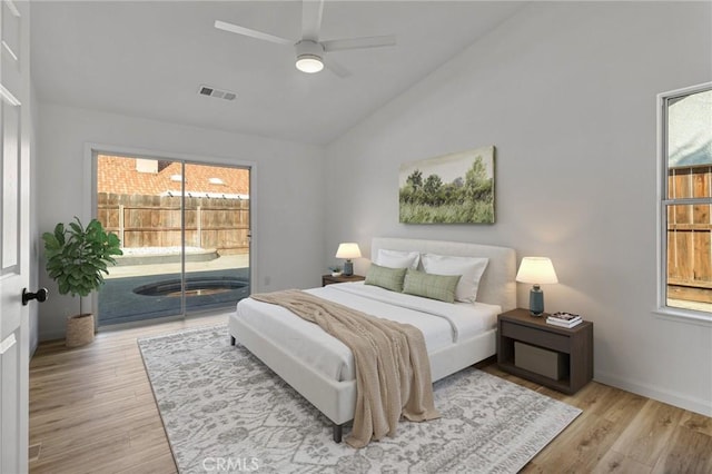 bedroom with access to exterior, light hardwood / wood-style floors, vaulted ceiling, and multiple windows