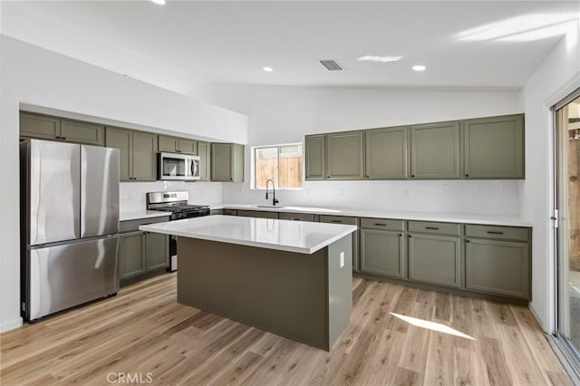 kitchen featuring sink, a center island, vaulted ceiling, light wood-type flooring, and appliances with stainless steel finishes