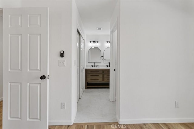 hallway featuring sink and light hardwood / wood-style floors