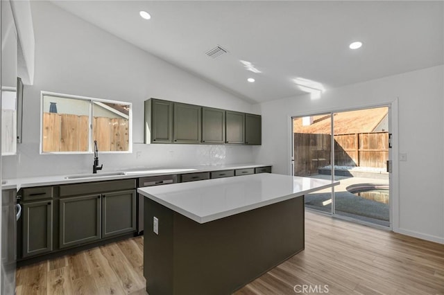 kitchen featuring sink, vaulted ceiling, light hardwood / wood-style flooring, a kitchen island, and backsplash