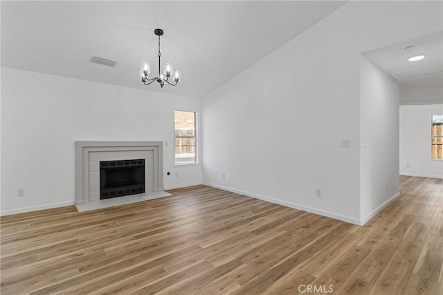 unfurnished living room with lofted ceiling, plenty of natural light, a tile fireplace, and wood-type flooring