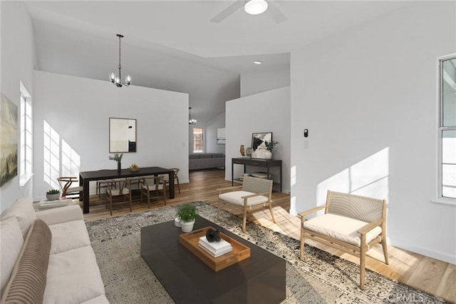 living room featuring ceiling fan with notable chandelier, wood-type flooring, and high vaulted ceiling