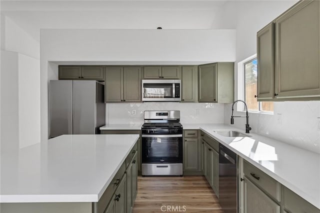 kitchen with tasteful backsplash, appliances with stainless steel finishes, sink, and hardwood / wood-style floors