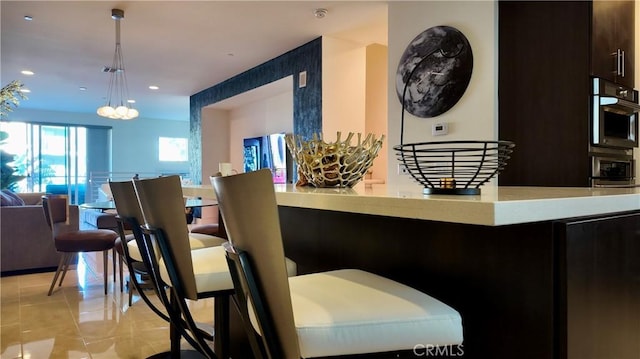 interior space featuring light tile patterned floors, decorative light fixtures, dark brown cabinets, and stainless steel double oven