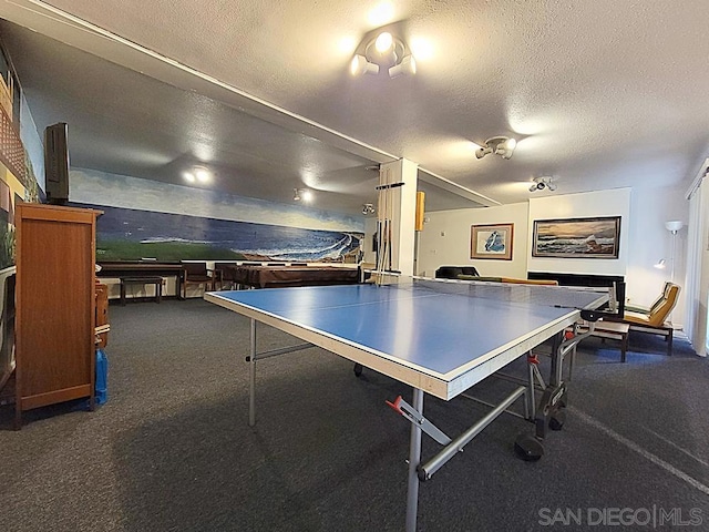 playroom with dark carpet and a textured ceiling