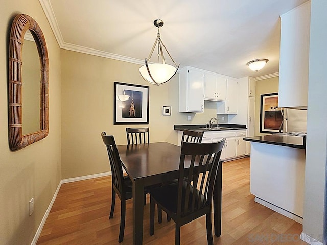 dining room featuring crown molding, sink, and light hardwood / wood-style flooring