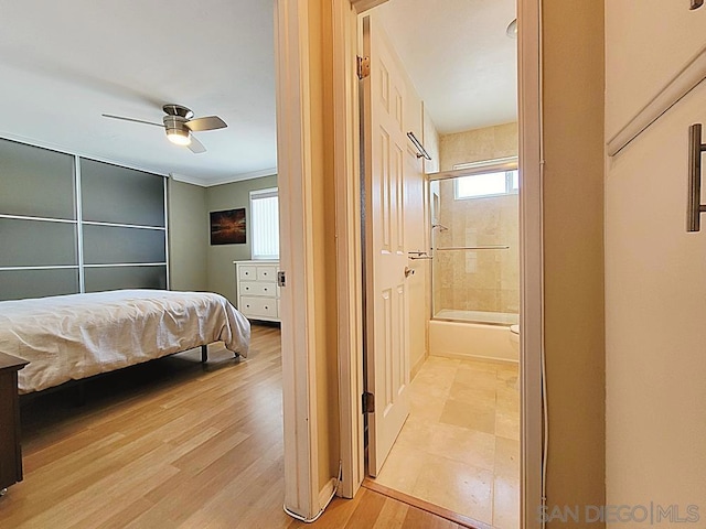 bedroom featuring ceiling fan, ensuite bath, and light wood-type flooring