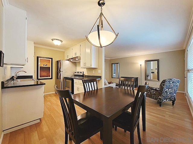 dining area featuring ornamental molding, sink, and light hardwood / wood-style floors