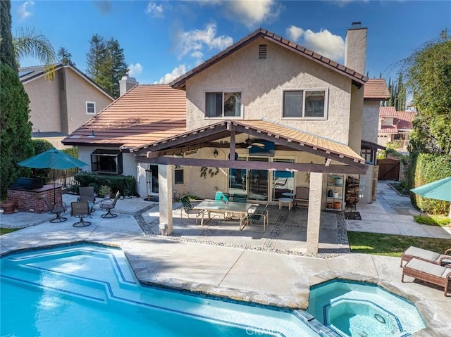 back of property featuring a swimming pool with hot tub and a patio