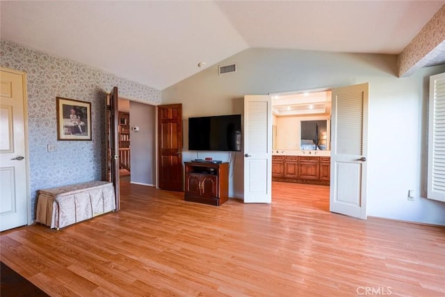 unfurnished living room with lofted ceiling, sink, and light wood-type flooring