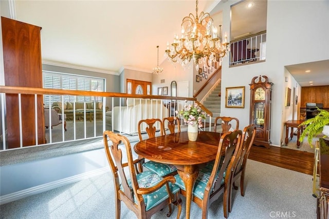 dining area with a towering ceiling, ornamental molding, and a chandelier