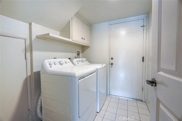 laundry area with cabinets, light tile patterned floors, and washing machine and clothes dryer