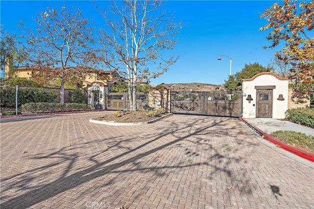 exterior space with street lighting, a gate, curbs, and a gated entry