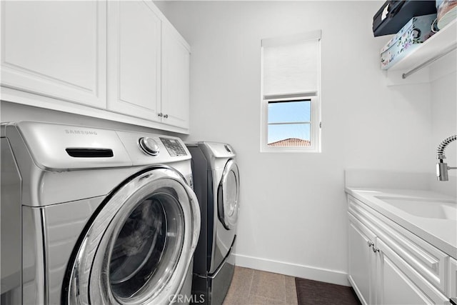 clothes washing area featuring a sink, cabinet space, baseboards, and washer and dryer