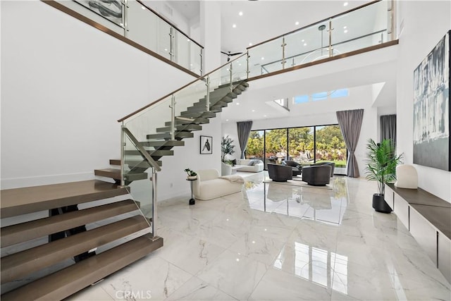 staircase with marble finish floor, a high ceiling, and baseboards