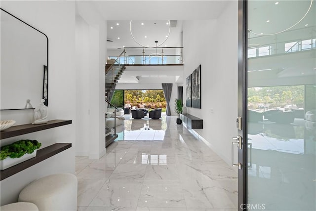 entryway featuring marble finish floor, a high ceiling, and baseboards