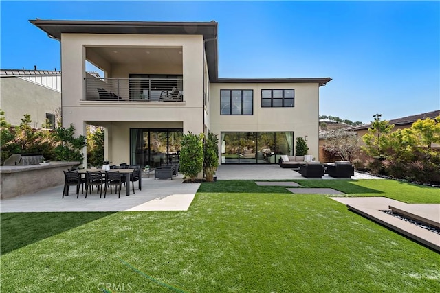 back of property with a balcony, stucco siding, an outdoor hangout area, and a yard