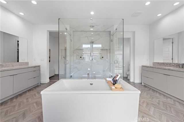 full bathroom with toilet, recessed lighting, a sink, two vanities, and a marble finish shower