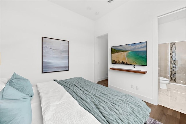 bedroom featuring ensuite bathroom, wood finished floors, and baseboards