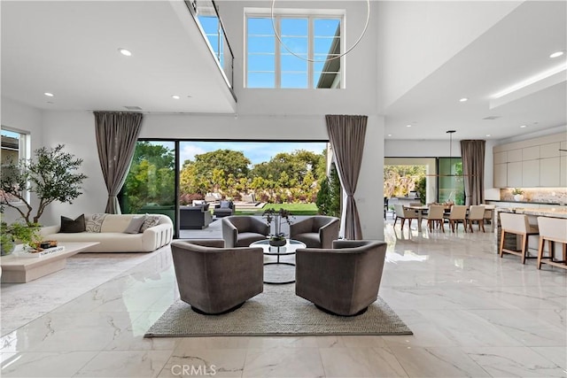 living room featuring a towering ceiling, marble finish floor, a wealth of natural light, and recessed lighting