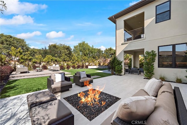 view of patio / terrace with a balcony and an outdoor living space with a fire pit