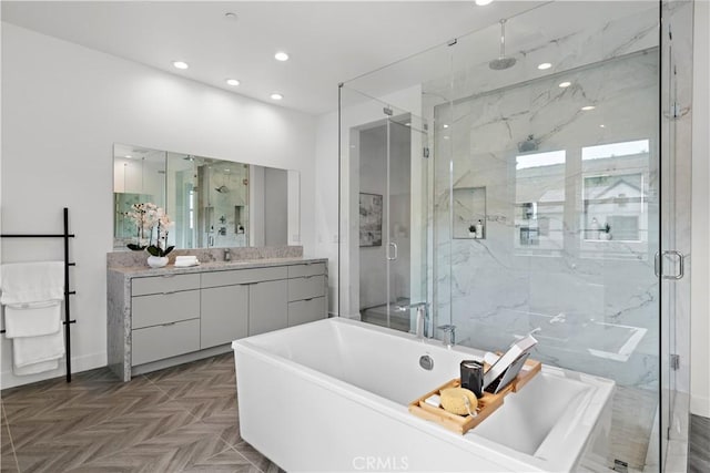 full bath featuring recessed lighting, a freestanding tub, vanity, and a marble finish shower