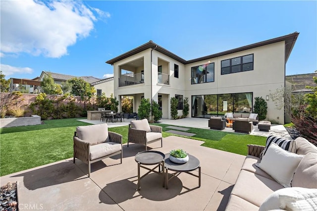 rear view of property with a patio, a yard, stucco siding, an outdoor hangout area, and a balcony