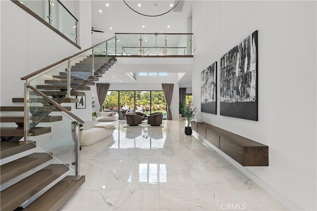 entryway featuring marble finish floor, stairway, a towering ceiling, and visible vents