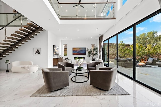 living area featuring a towering ceiling, marble finish floor, stairs, and recessed lighting