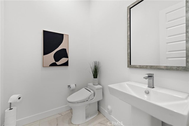 bathroom featuring marble finish floor, baseboards, a sink, and toilet