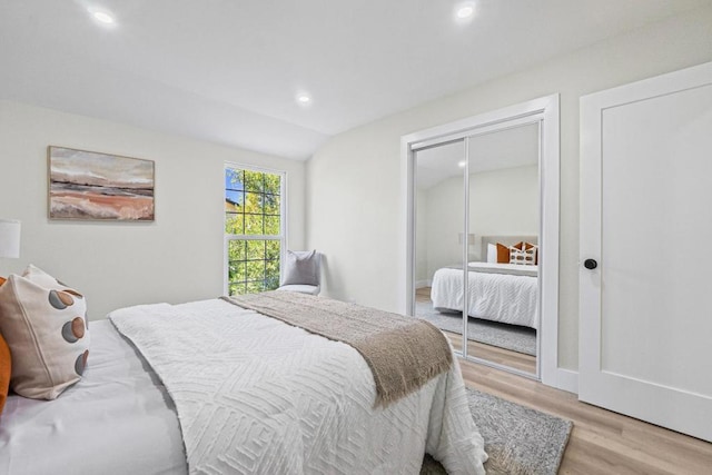 bedroom featuring vaulted ceiling, light hardwood / wood-style floors, and a closet