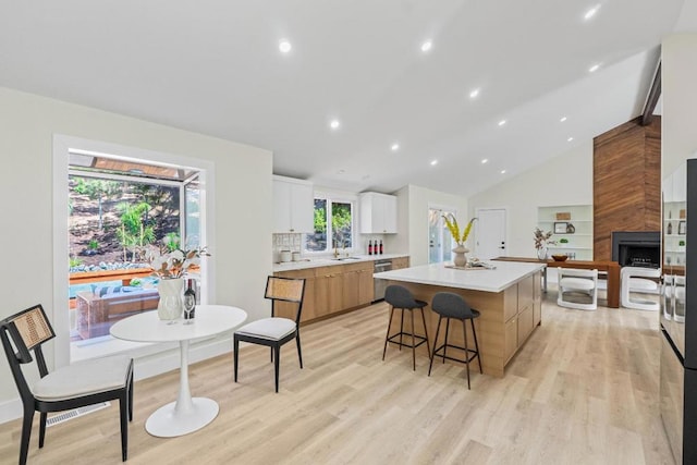 kitchen featuring a kitchen bar, sink, dishwasher, a kitchen island, and white cabinets