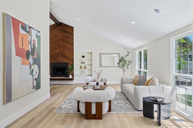 living room featuring built in features, a fireplace, high vaulted ceiling, and light hardwood / wood-style flooring