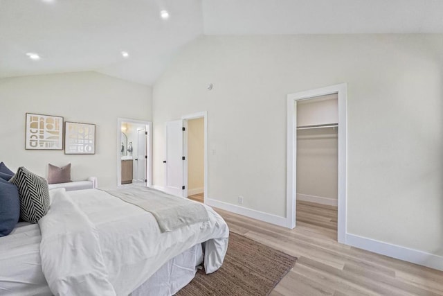 bedroom featuring connected bathroom, a spacious closet, vaulted ceiling, and light hardwood / wood-style floors