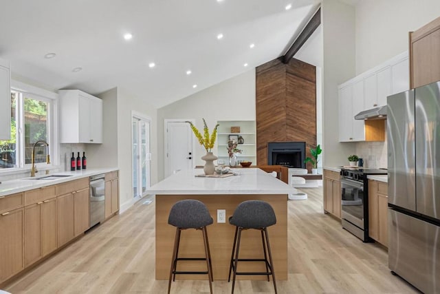 kitchen with sink, white cabinetry, a kitchen island, stainless steel appliances, and light hardwood / wood-style floors