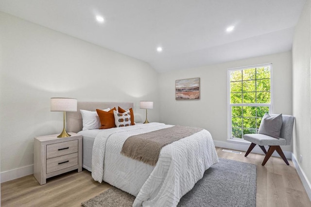 bedroom with multiple windows, vaulted ceiling, and light wood-type flooring