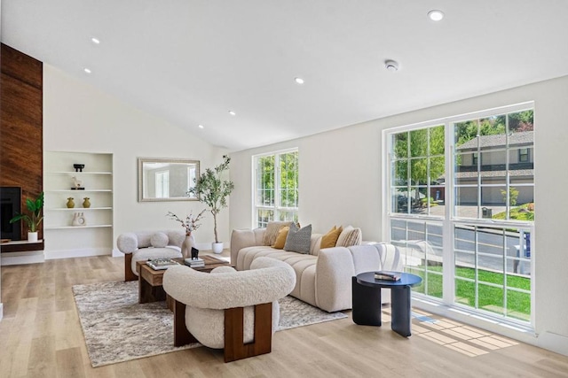 living room featuring high vaulted ceiling, built in features, and light hardwood / wood-style floors